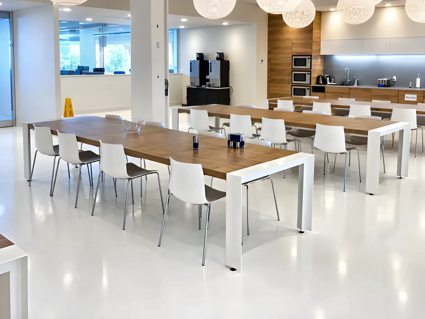 The lunch room at Aritzia’s head office, long tables and white chairs on the white urethane floor West Pacific installed