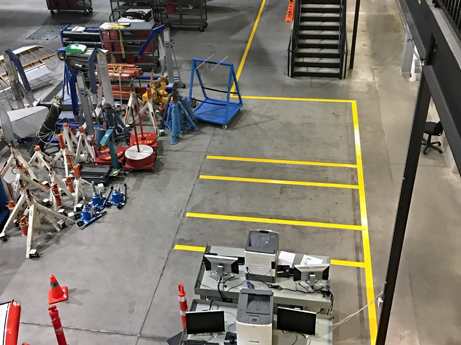 Yellow urethane bay lines on the polished hangar floor by the stairs, BCIT Aerospace Technology Campus, Richmond