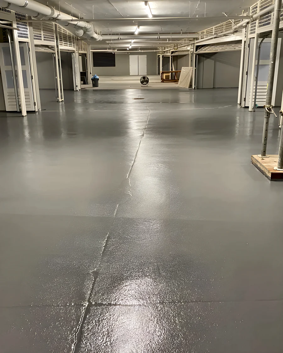 Finished grey Tremco traffic coating down an aisle between rows of doors to the double doors, 2289 Bellevue Avenue parkade