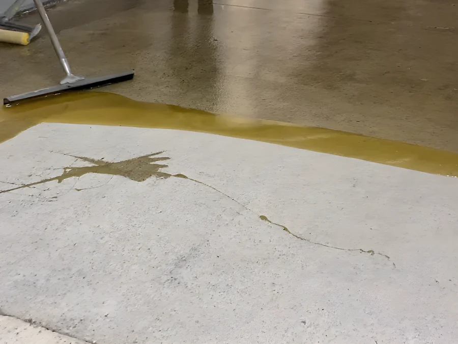 The first coat of the Tremco traffic coating squeegeed out over bare concrete and into its cracks, 2289 Bellevue Avenue parkade