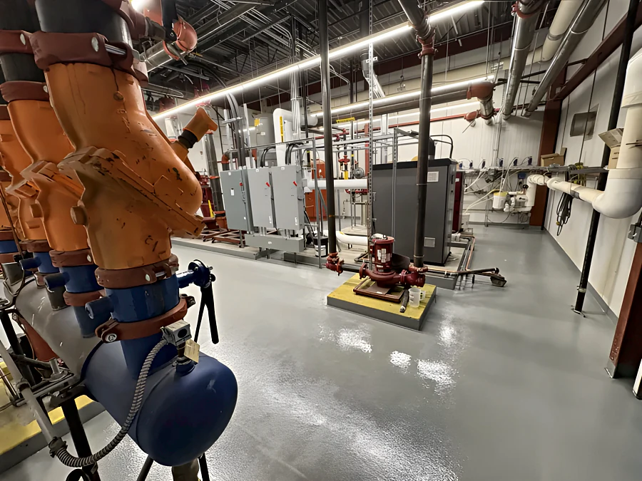 Finished grey traffic coating across a Canadian Tire mechanical room floor, running between equipment plinths, switchgear and a base-mounted pump