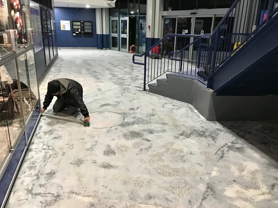 A crew member detailing the edge along the glazing as the concourse slab at Canlan Ice Sports in Burnaby is prepared for epoxy