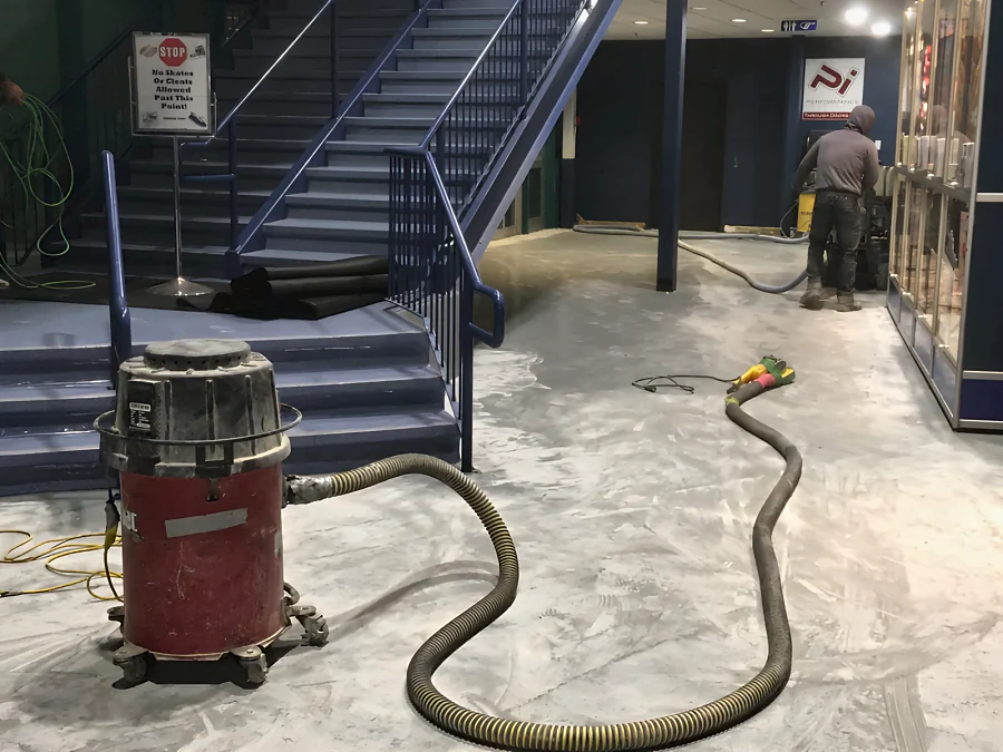 The concourse at Canlan Ice Sports in Burnaby being ground under dust extraction before the epoxy, the extractor and hose in front