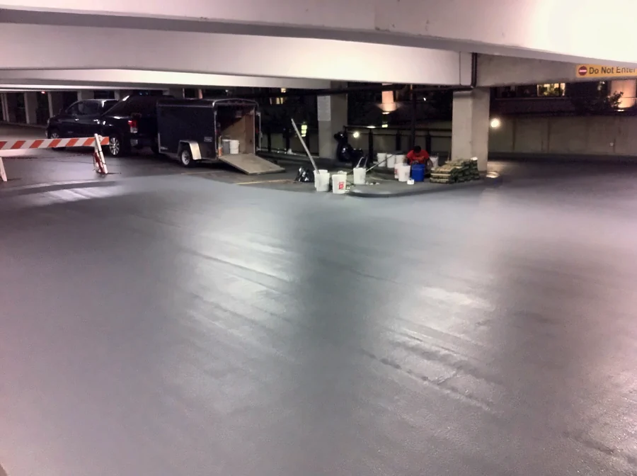 The traffic coating going down across a level of the Central City parkade in Surrey at night, the crew mixing materials beside the trailer
