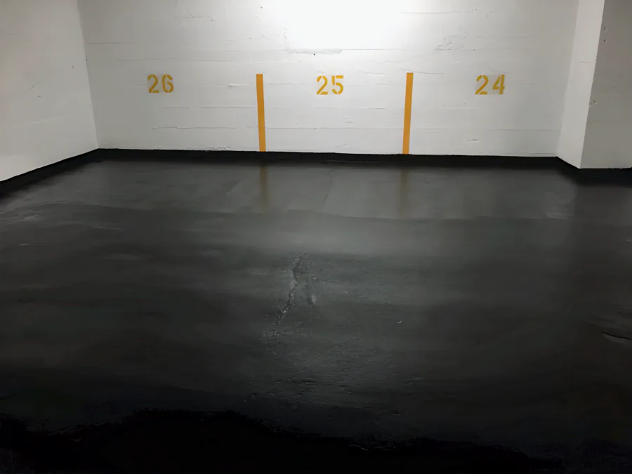 Black traffic coating in stalls 24 to 26 of a Downtown Vancouver parkade, carried to the wall as a black cove