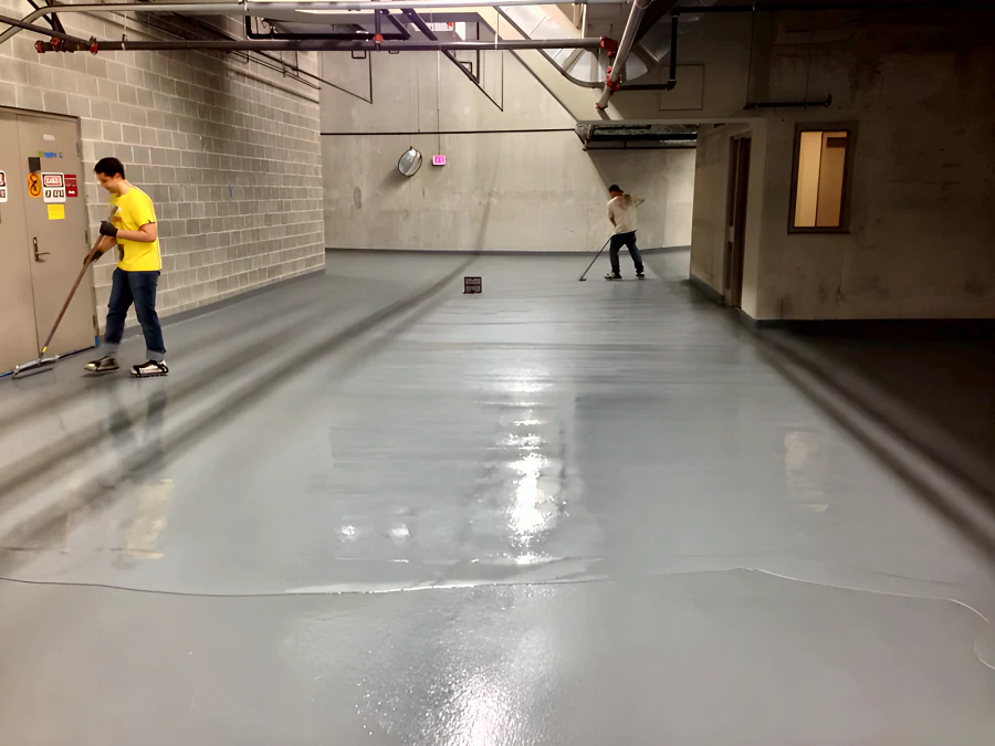 Crew applying the recoat by squeegee and roller along a Downtown Vancouver parkade, past the electrical room door