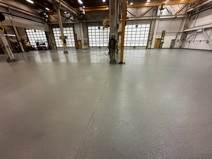 The finished ResinTech EWS floor across a Finning heavy-equipment workshop to the roller doors of bays 13 to 16