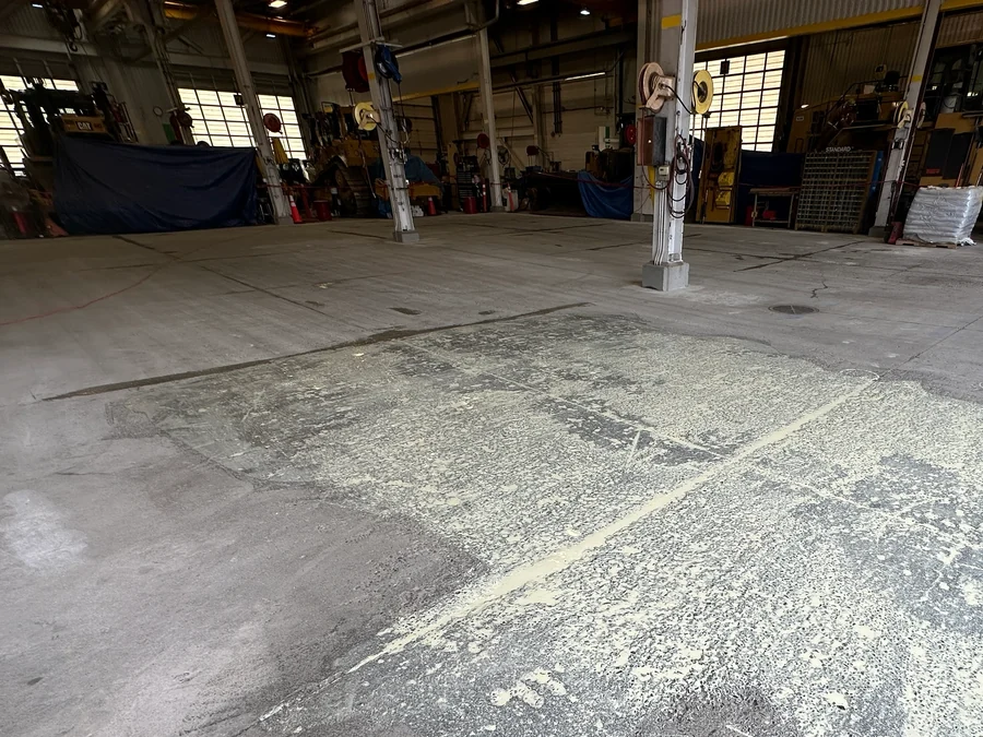 The old floor coating stripped back to the concrete in a Finning heavy-equipment workshop before the ResinTech EWS floor