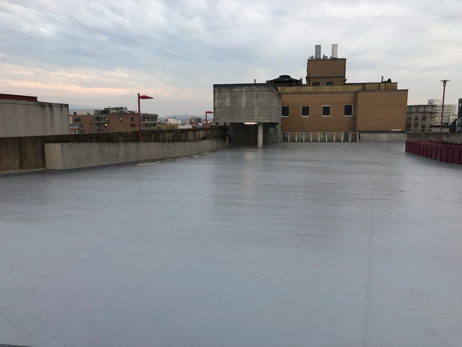 The finished grey Tremco Vulkem coat across the Gastown parkade roof deck to the stair tower, Vancouver