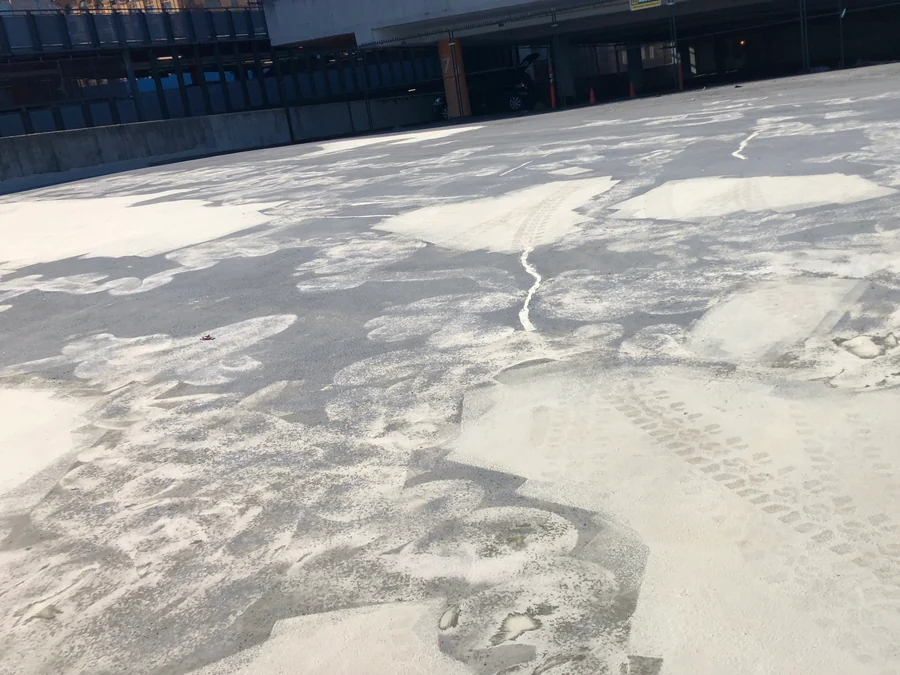 The old coating being removed from the parkade roof deck in Gastown, Vancouver, bare concrete showing through before the recoat