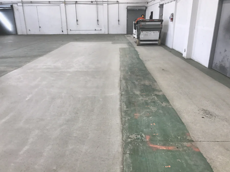 A ride-on shot blaster taking an old green floor coating off a commercial slab in Grandview, Vancouver