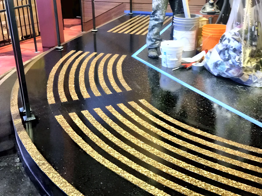 Curved gold flake warning strips set into a black random flake floor at Hard Rock Casino Coquitlam, mid-installation