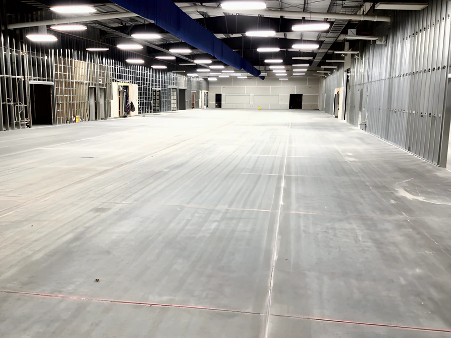 Bare concrete slab in the MTU Canada building in Richmond before coating, with saw-cut joints, red layout lines and steel stud walls going up on both sides