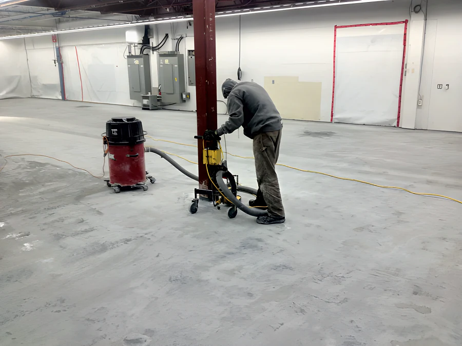 Edge grinding around a steel column with a dust extractor in Building 2 at MTU Maintenance Canada in Richmond, inside plastic containment walls