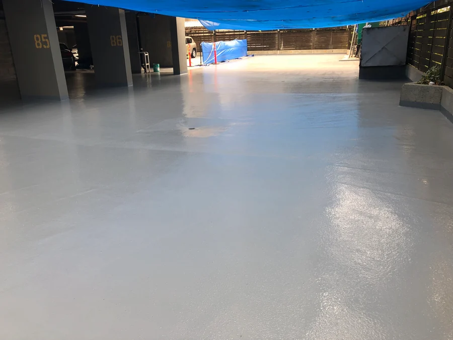 The finished grey traffic coating across a half-open parkade level in New Westminster, tarped overhead while it cured