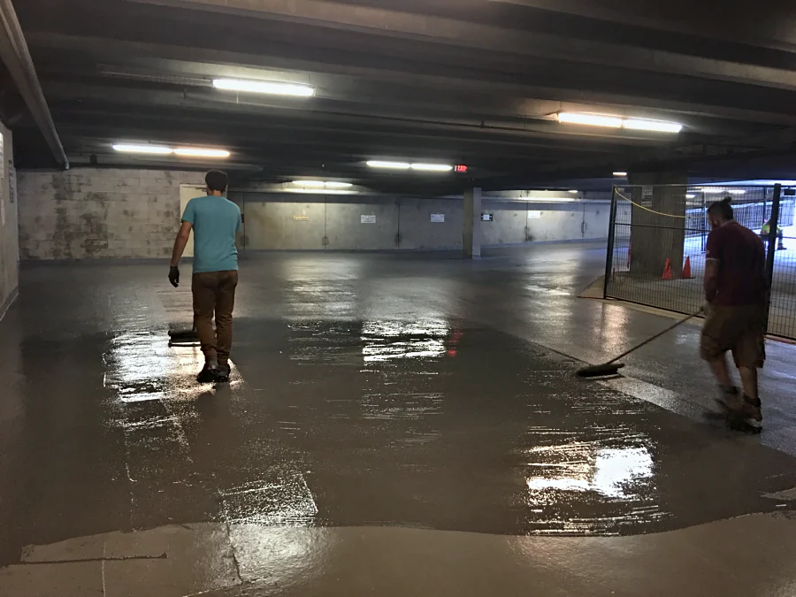 The crew spreading a Tremco Vulkem traffic coating by squeegee and roller across a North Vancouver parkade level