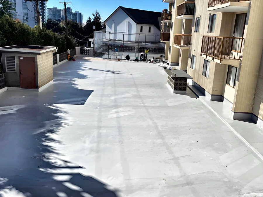 Resurfaced outdoor pedestrian deck beside a residential building, finished in a light grey traffic coating