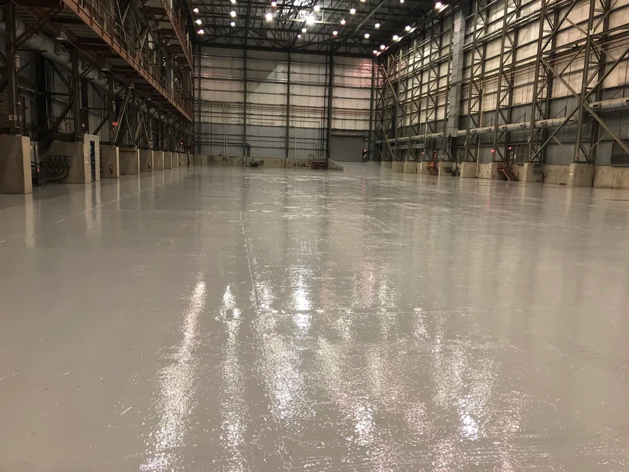 The finished grey epoxy floor across the hall with the lights reflected in it, Seaspan, North Vancouver, 2018