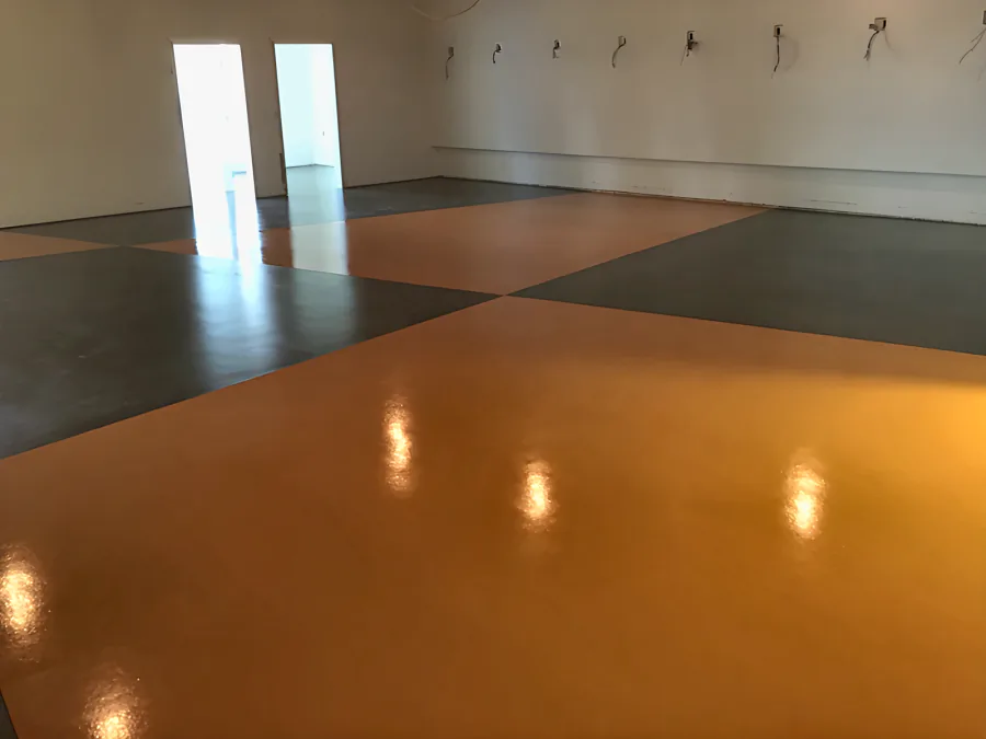 High-gloss orange and charcoal urethane floor meeting at a point in the middle of a showroom