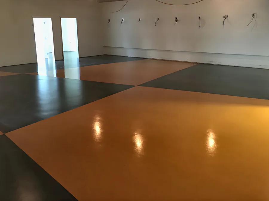 Showroom floor in urethane coatings, laid out in large orange and charcoal diagonal sections under the track lighting