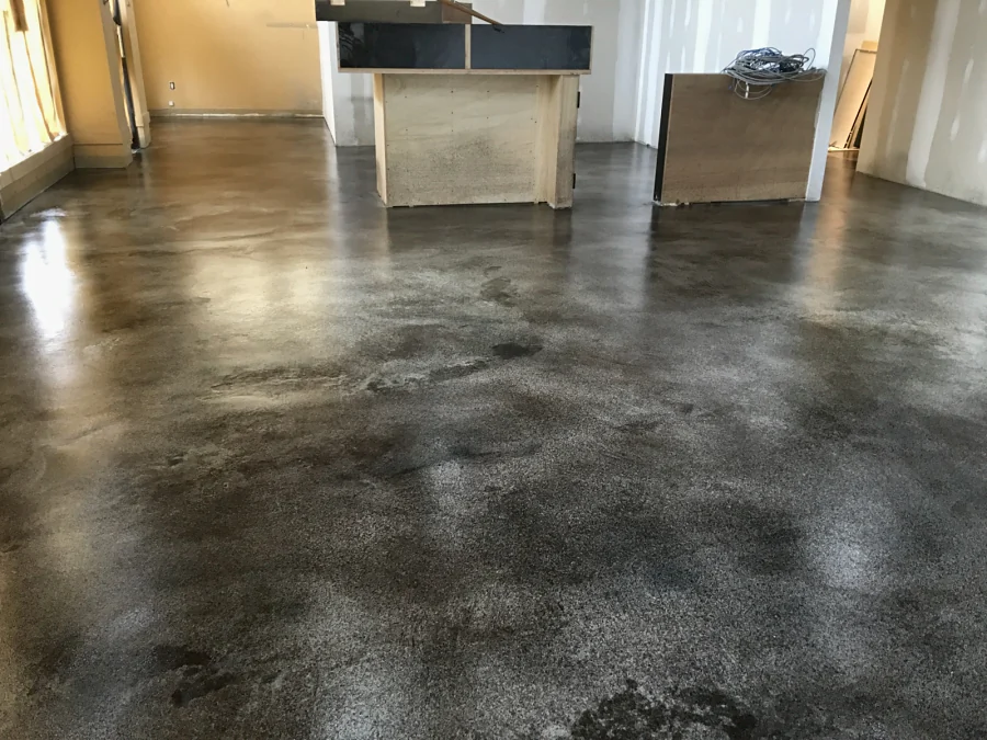 A commercial fit-out floor finished in self-levelling topping, stained in mottled brown and grey and polished, the counters going in