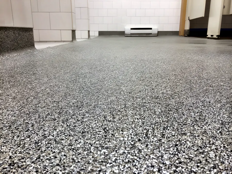 Sika decorative quartz floor running the length of a school washroom in Surrey, in a textured multi-coloured quartz finish