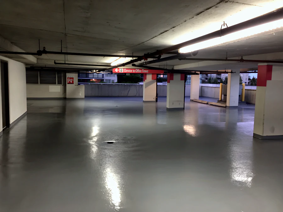 A freshly coated level of the Three West Centre parkade in Richmond, glossy under the lights, red-banded columns beyond