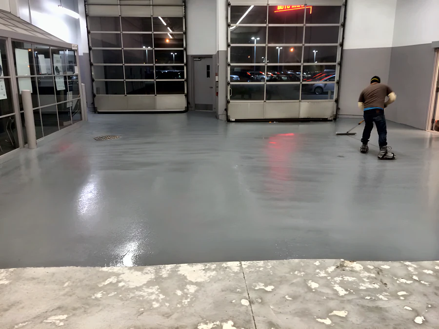 Fresh grey traffic coating going down across the service drive of a Toyota dealership’s old shop in Vancouver, with the prepared concrete still bare in front