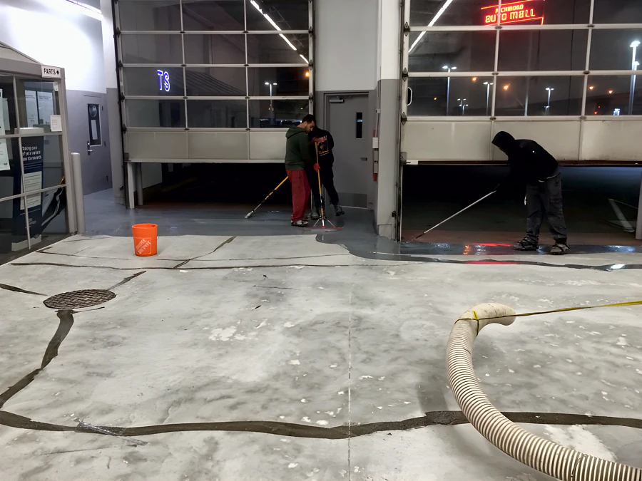 Crew laying the traffic coating at the roll-up doors of a Toyota dealership’s old shop in Vancouver, over a slab with its cracks filled