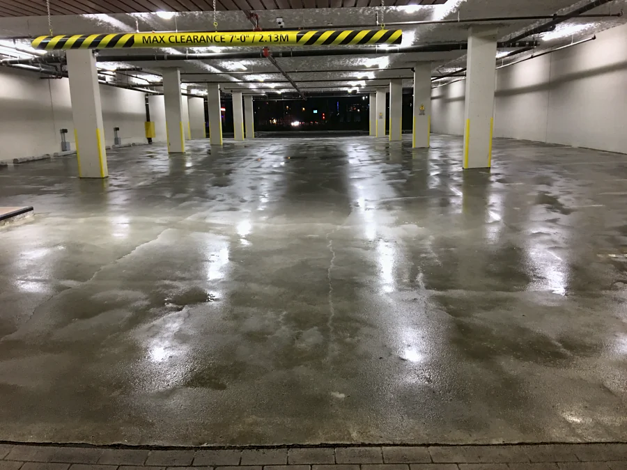 The shot-blasted parkade floor at the Trail Appliances store in Richmond at night, wet under the lights