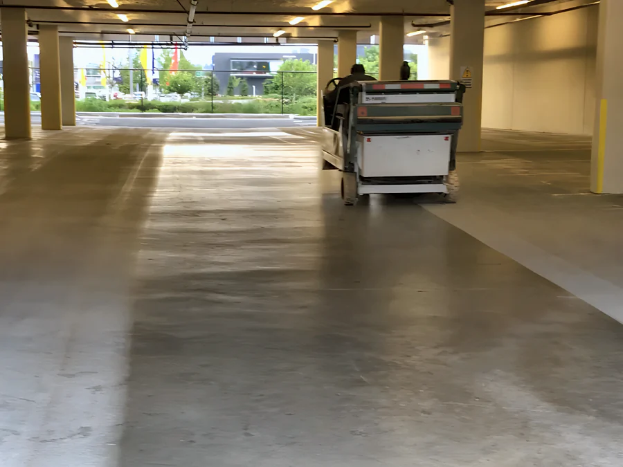 A ride-on shot blaster working through the Trail Appliances parkade in Richmond, the blasted lanes lighter than the untouched concrete