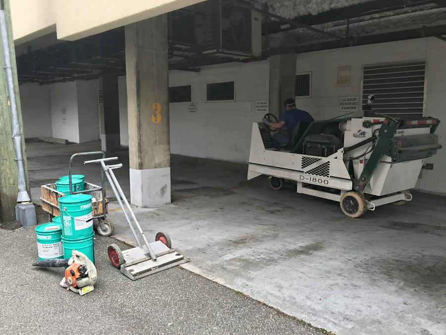 A ride-on shot blaster preparing the covered loading bay of a Vancouver building, the Tremco materials staged at the lane