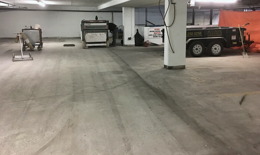 A Vancouver parkade slab after shot blasting, the blast lanes showing, the ride-on shot blaster and a West Pacific Coatings trailer beyond