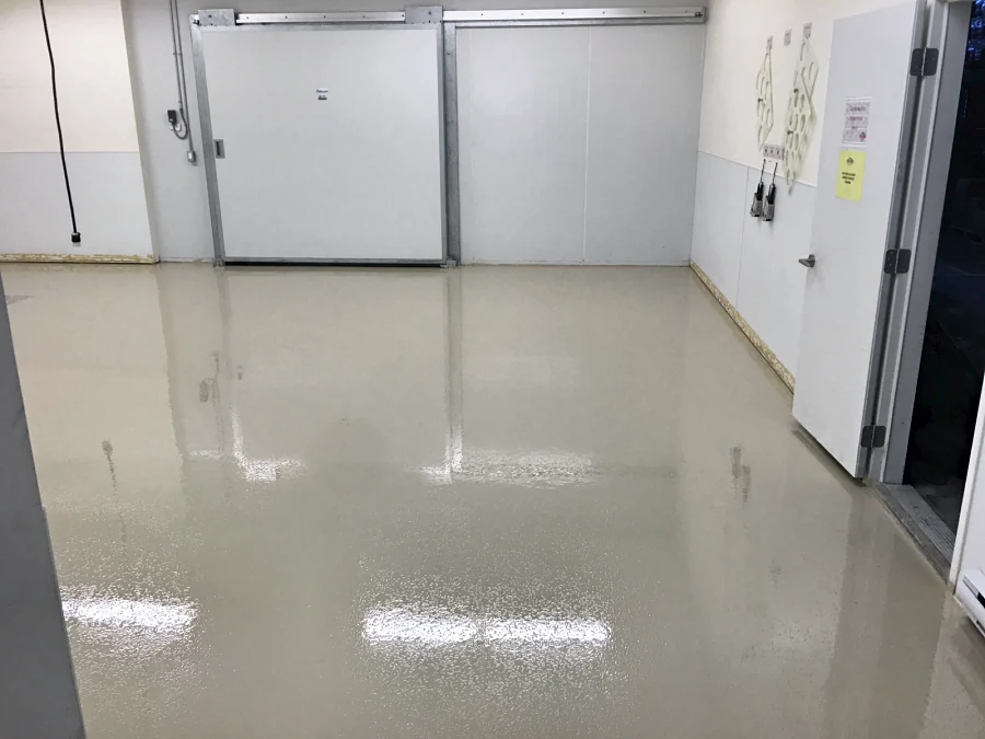 The finished walk-in cooler floor, ResinTech TUE top-coated with ResinTech CRU, running to the sliding cooler doors