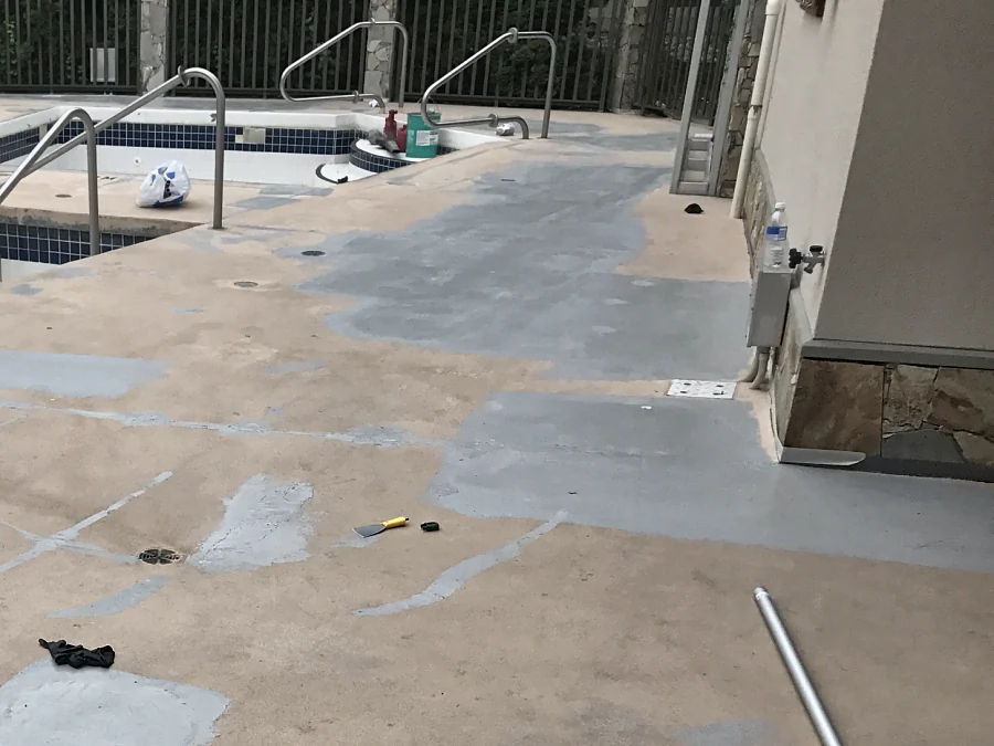 Cracks and damaged areas on a Whistler hotel pool deck filled and patched in grey before the ResinTech recoat